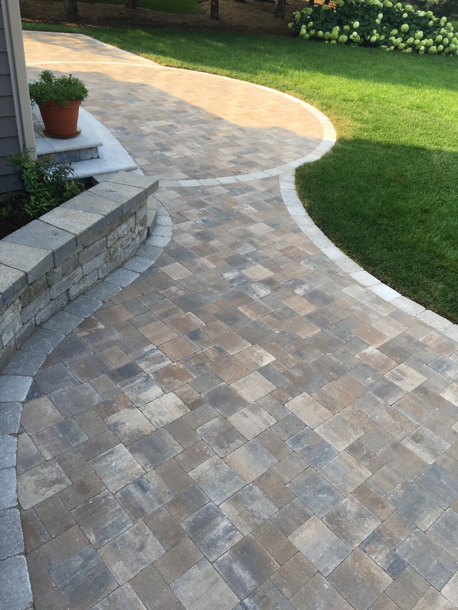 Paver patio with curved pathways and green lawn